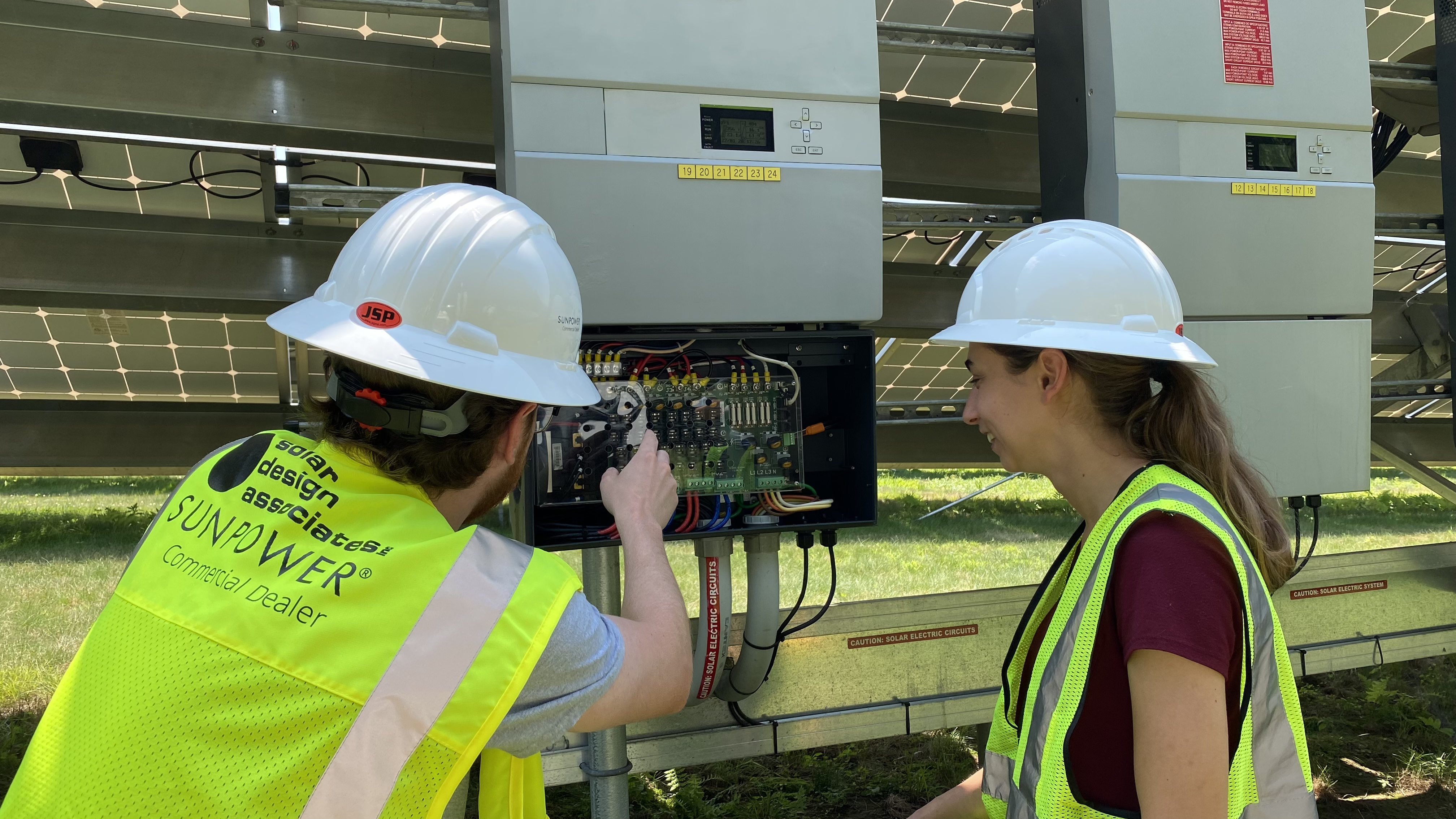 Two workers adjust high-voltage wiring for solar array