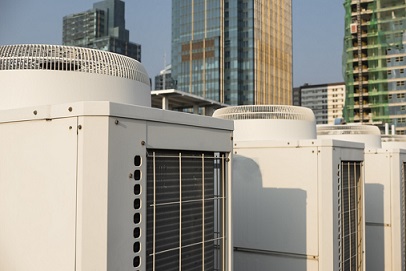 Rooftop closeup of commercial heat pump system with tall buildings in background