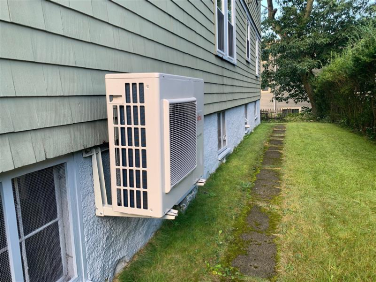 Outdoor air source heat pump unit on side of house