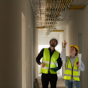 Engineers in hard hats inspecting piping on ceiling