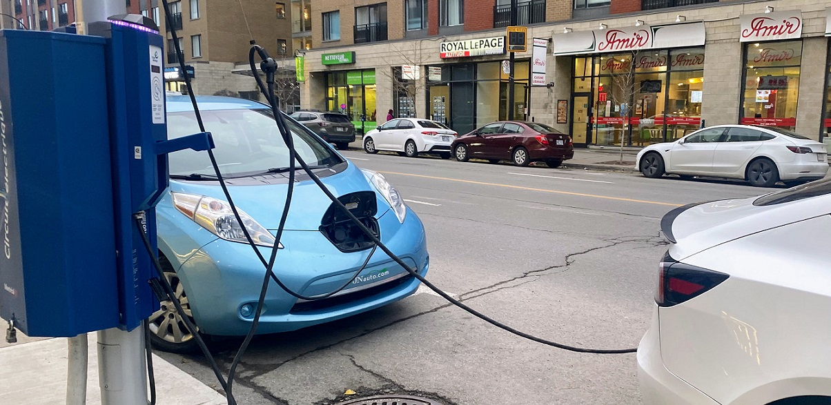 Street scene with two cars plugged into curbside charging station