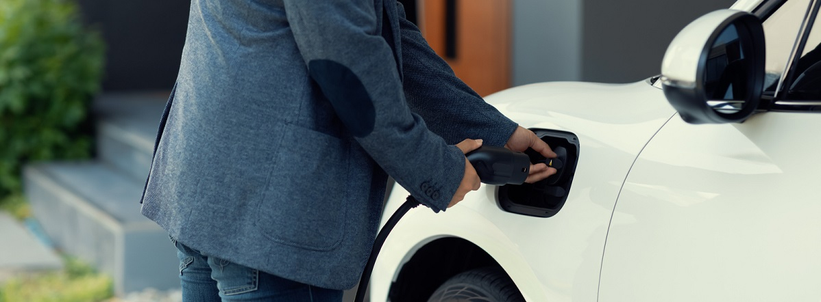 Man in sports jacket plugging in a car outside a house